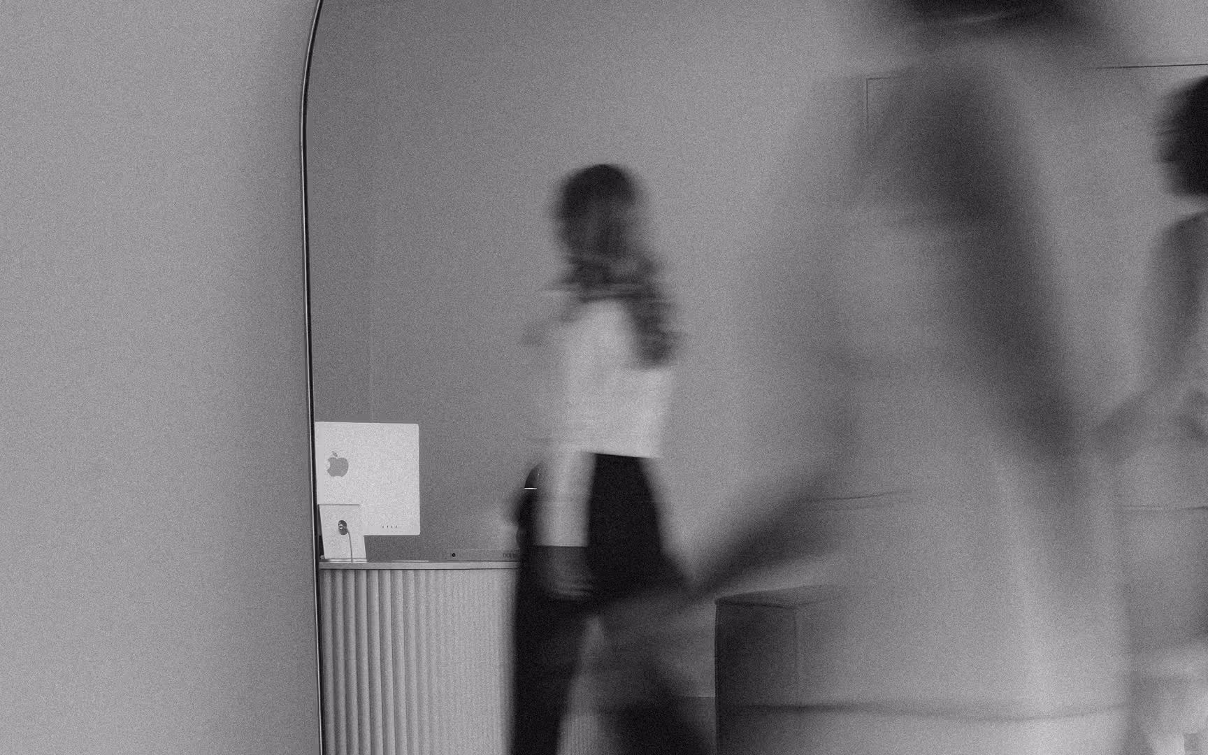 A figure passing an arched mirror, blurred in motion